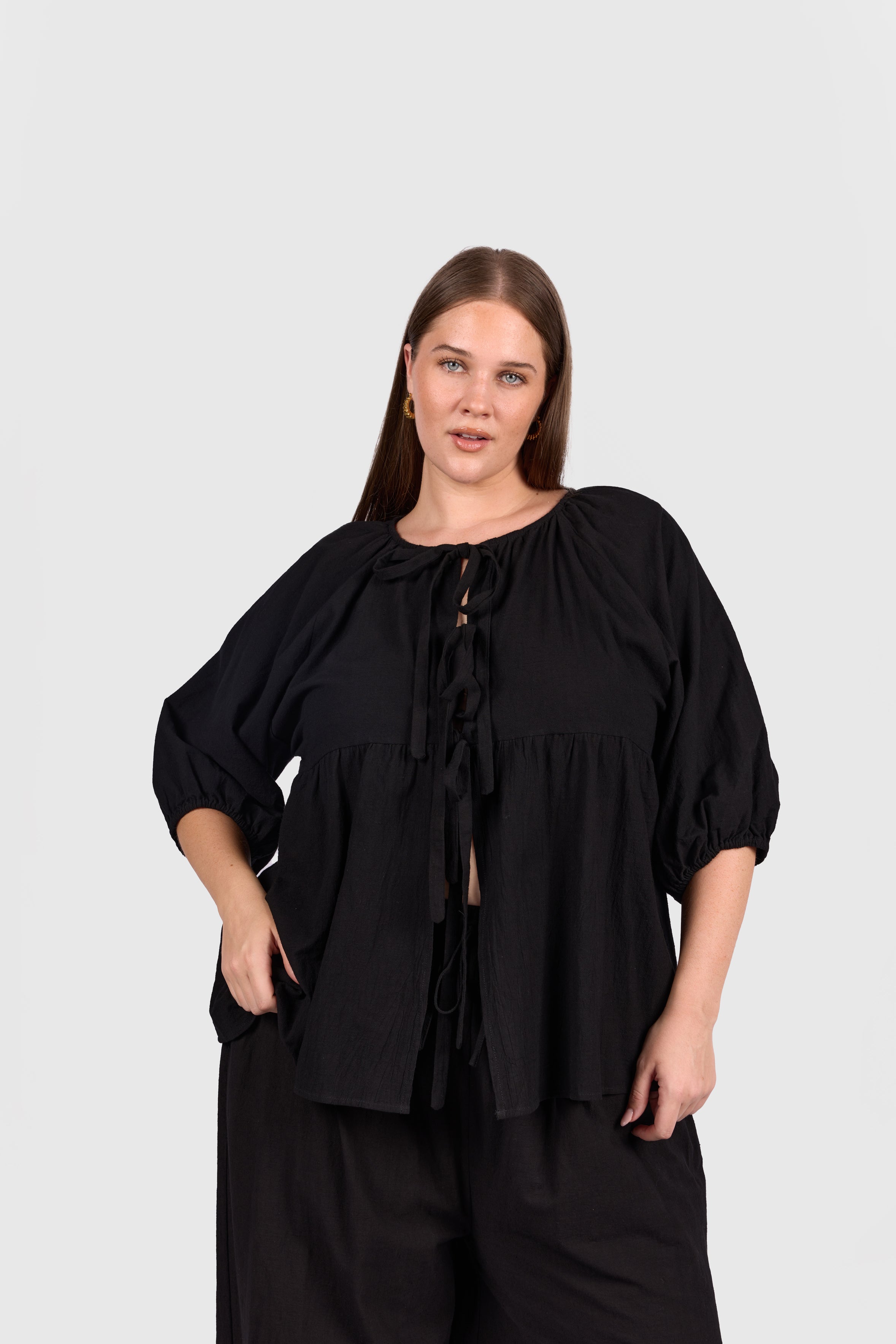 Woman wearing black tie up peplem style shirt.