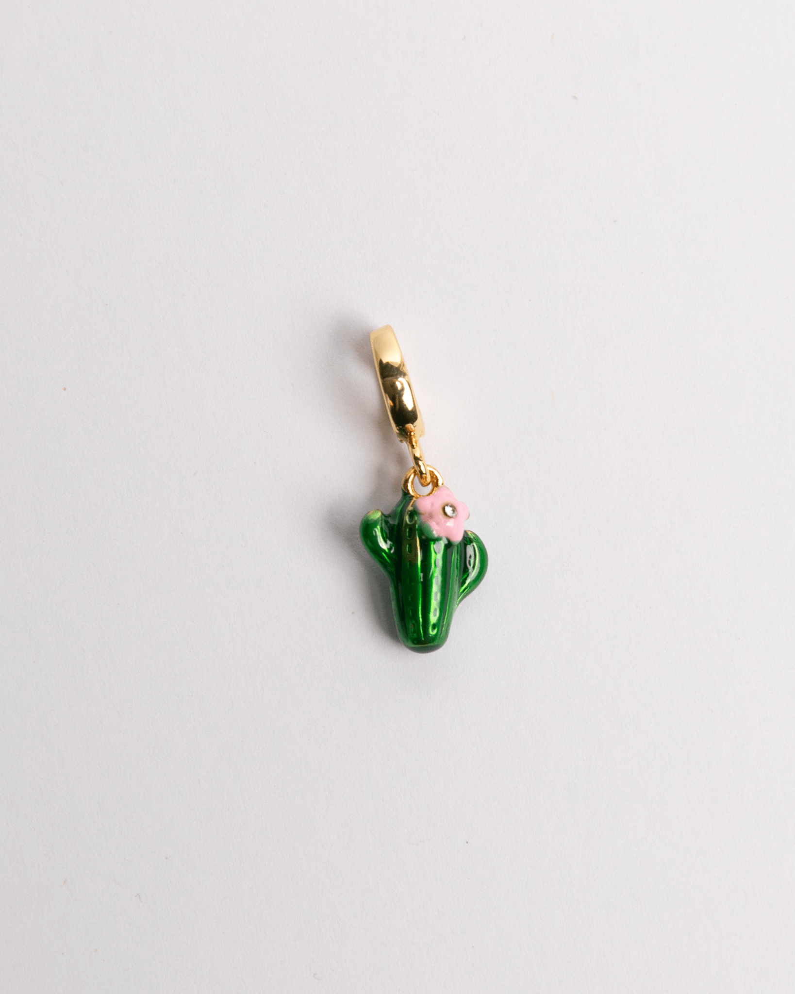 A green cactus charm with a pink flower on top, attached to a gold-colored chain eyelet, displayed against a white background.