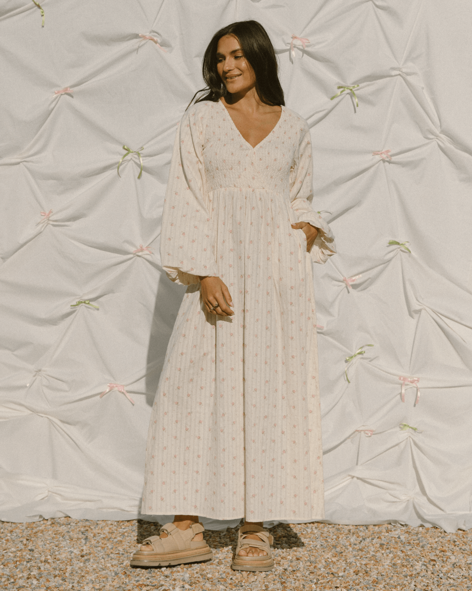 Woman wearing long-sleeved maxi dress with shirred breastfeeding access bust.