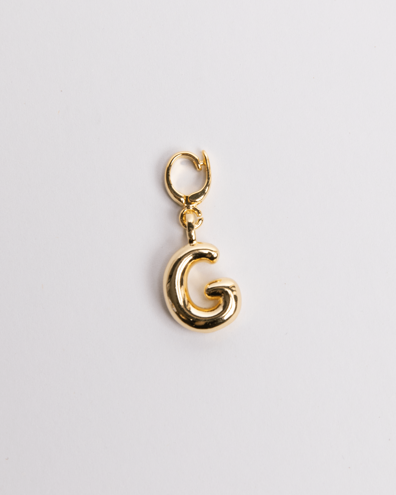 A gold-colored charm in the shape of the letter G with a secure clasp designed for attaching to necklaces or bracelets.
