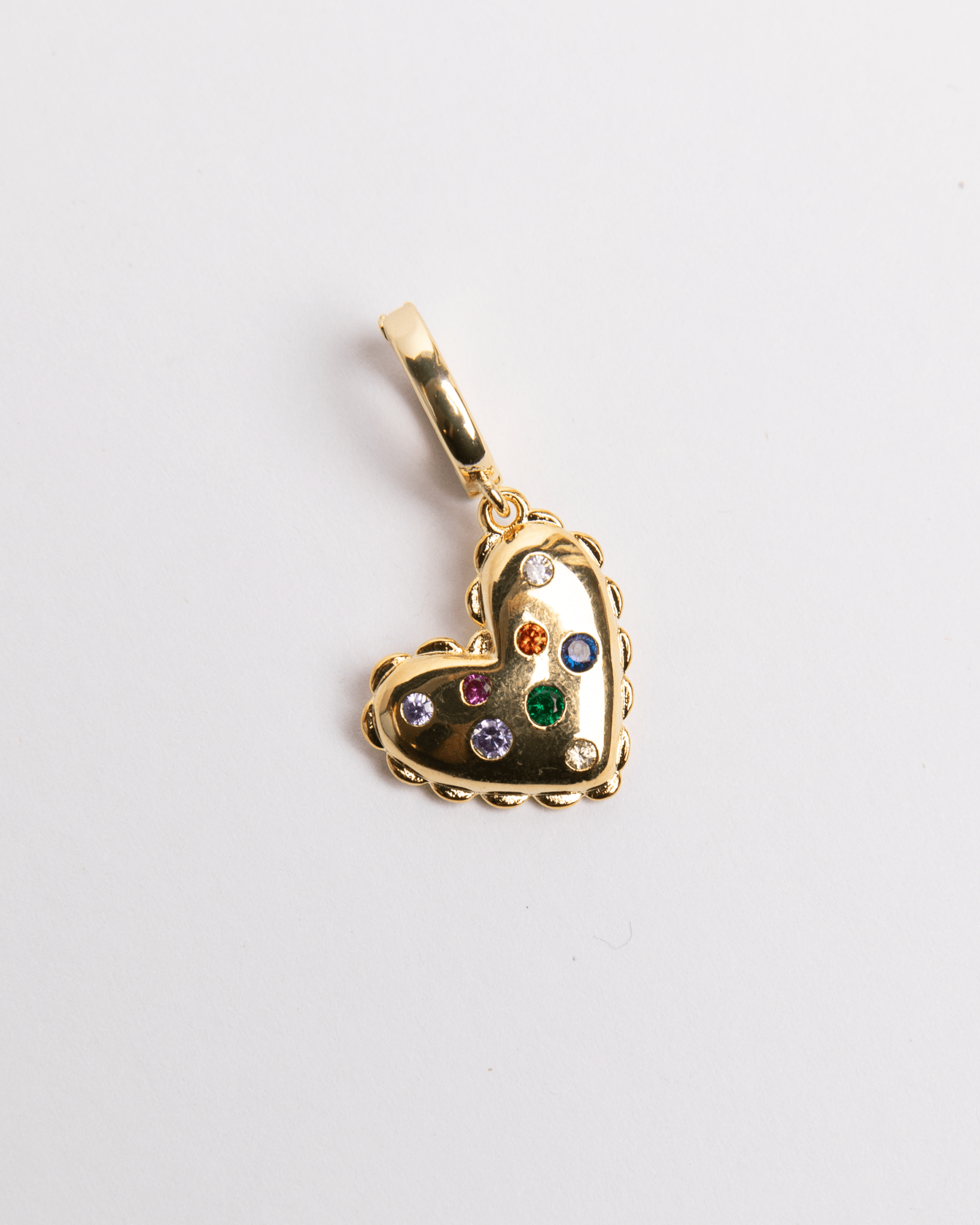 A gold-plated stainless steel heart-shaped charm with multicolored gemstones inlayed on it.