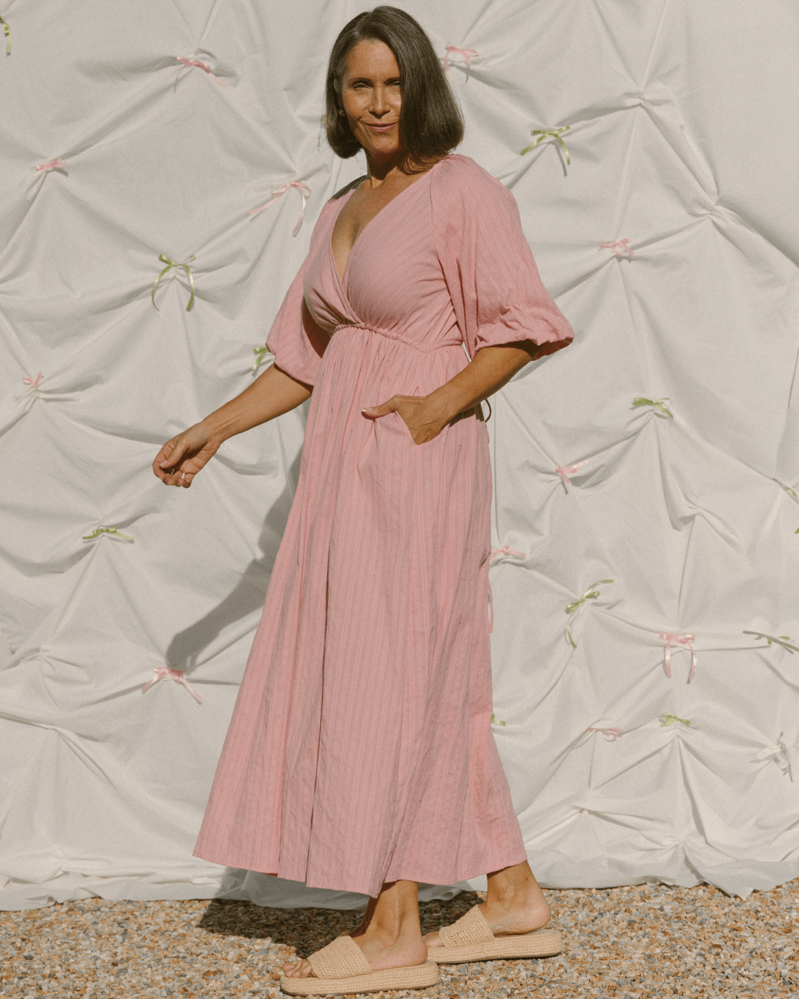 Woman wearing stylish pink dress with side pockets and an adjustable waist.