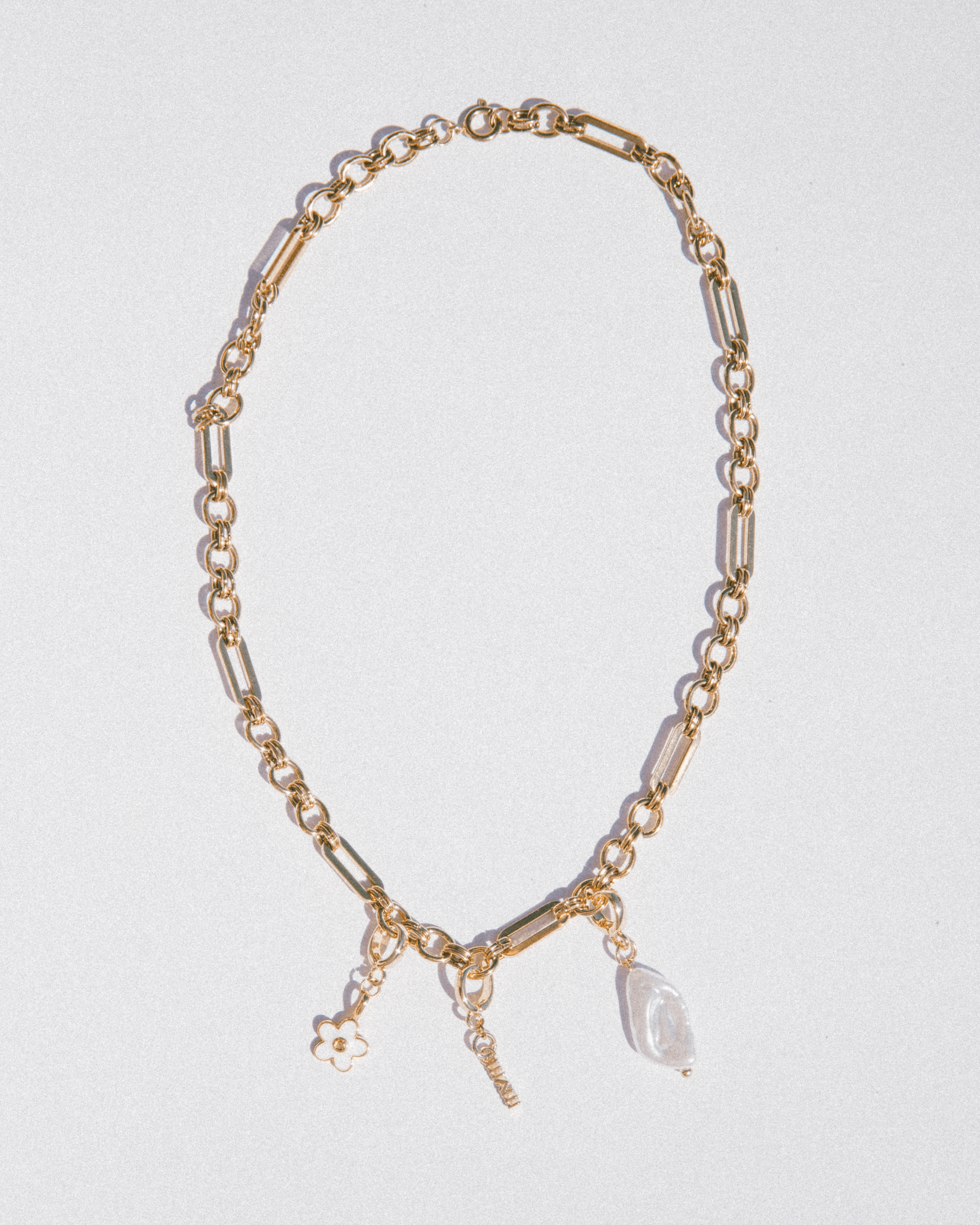 Gold chain necklace with pendant on a light gray background