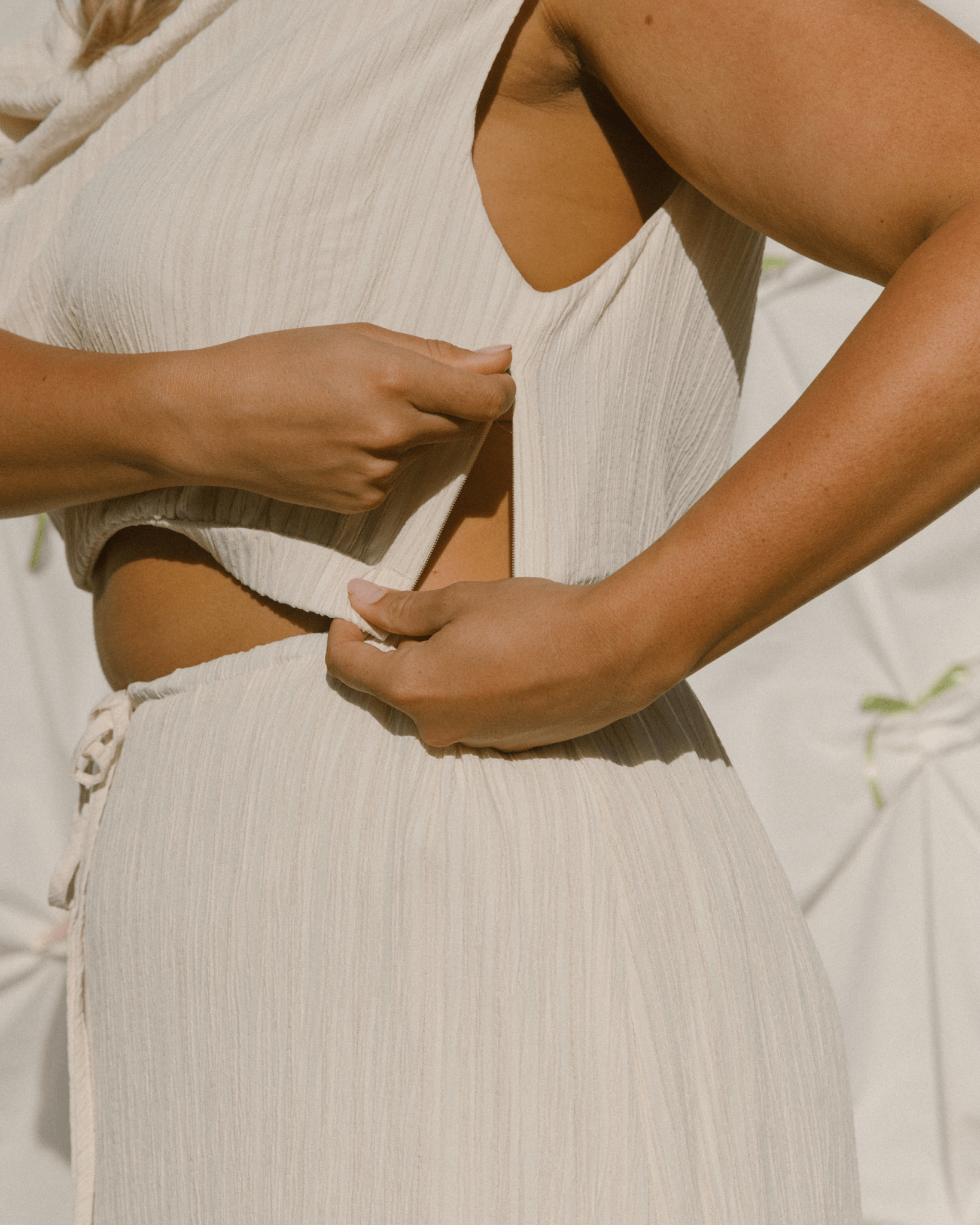 Close-up of a person wearing a cream crop top and showing breastfeeding side zippers.