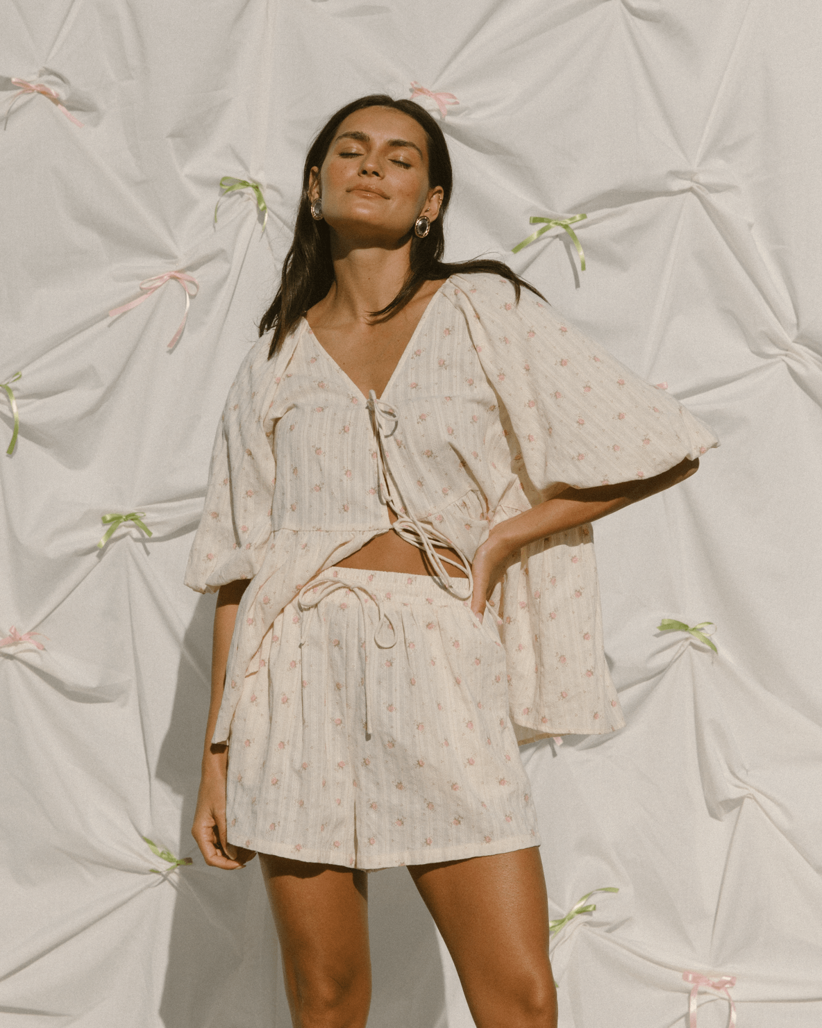 Woman wearing a cottage-core matching co-ord set with tie-up shirt with billowing sleeves and shorts.
