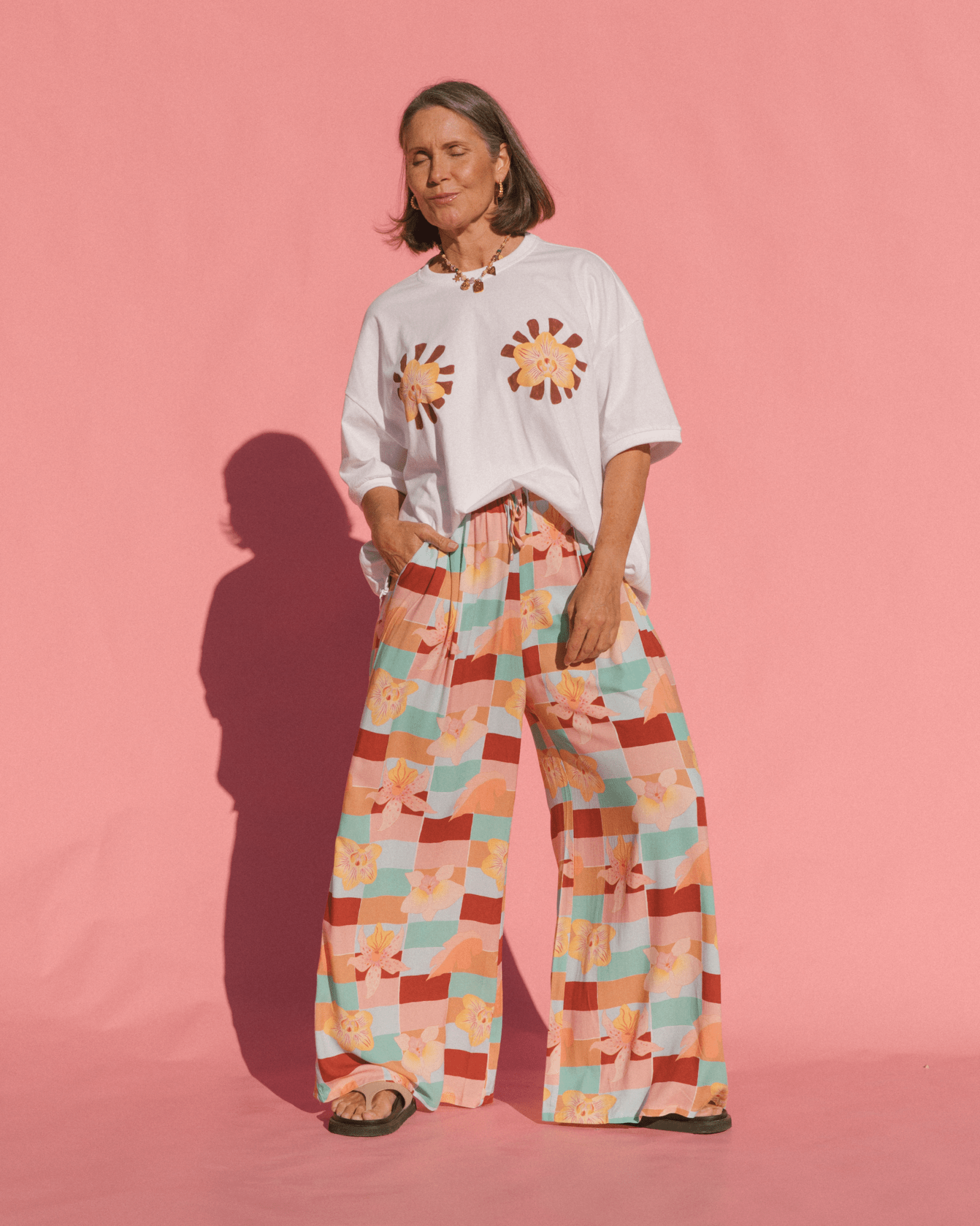 Woman wearing high waisted flowy pants in a spring pattern with pockets.