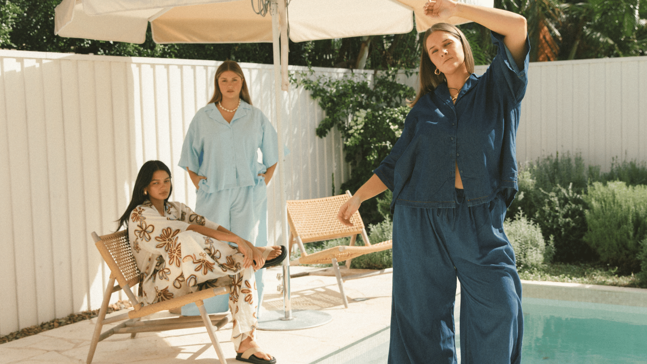 Three women wearing linen printed sets, relaxed sitting on stairs outside in a fashionable manner
