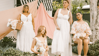 Four women wearing floral and floaty outfits in a garden