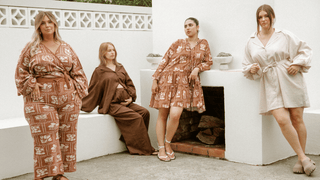 Four women in a backyard area styled in a netural clothing collection in unison, posing and modelling