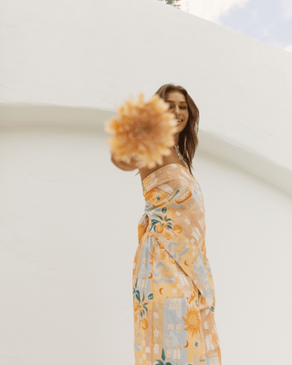 A girl holding out a flower to the camera, wearing a colourful matching set