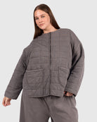 Woman wearing a size inclusive charcoal colour quilted jacket. 