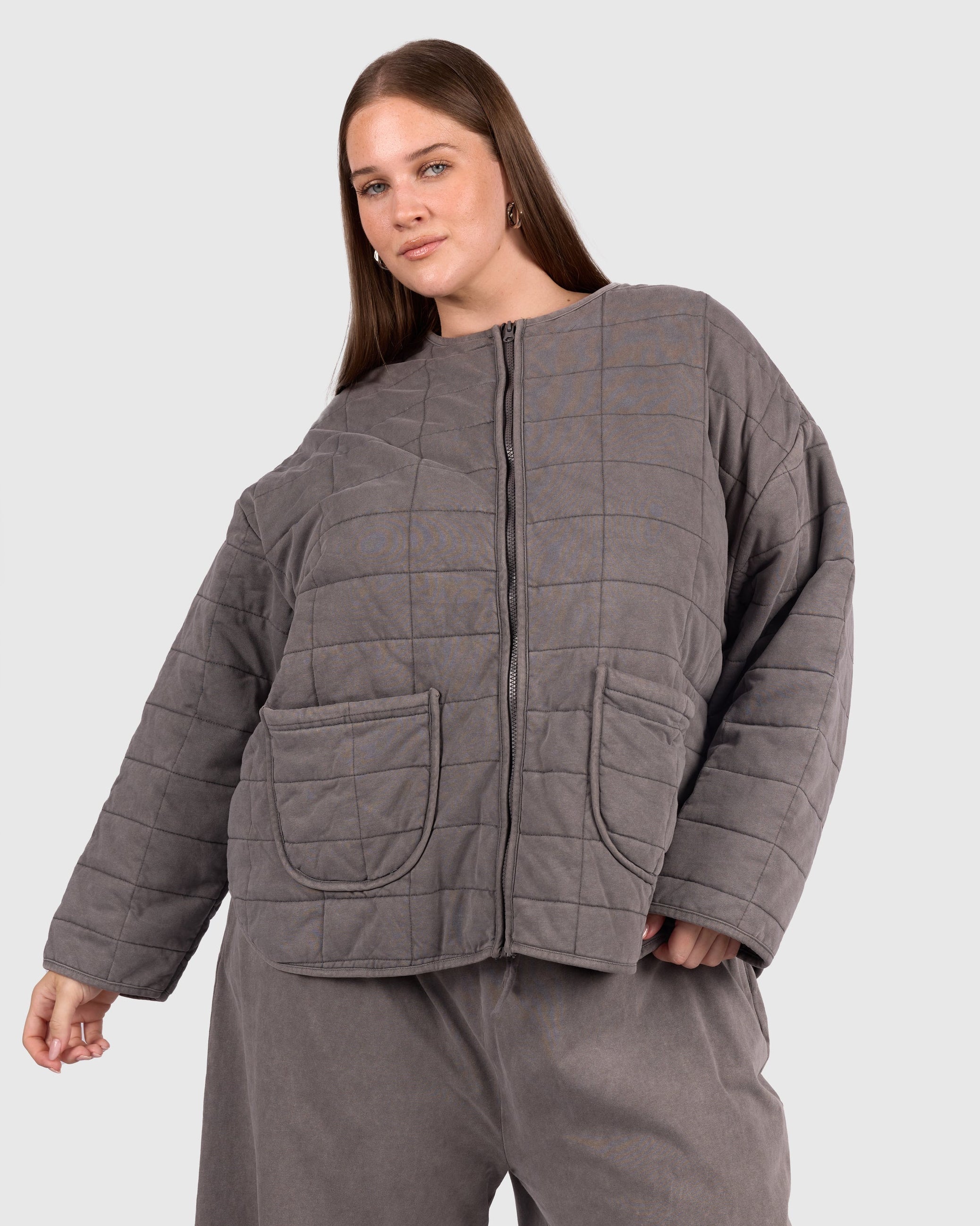Woman wearing a size inclusive charcoal colour quilted jacket. 