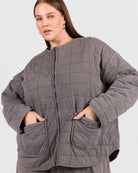Woman wearing a gray quilted jacket on a white background