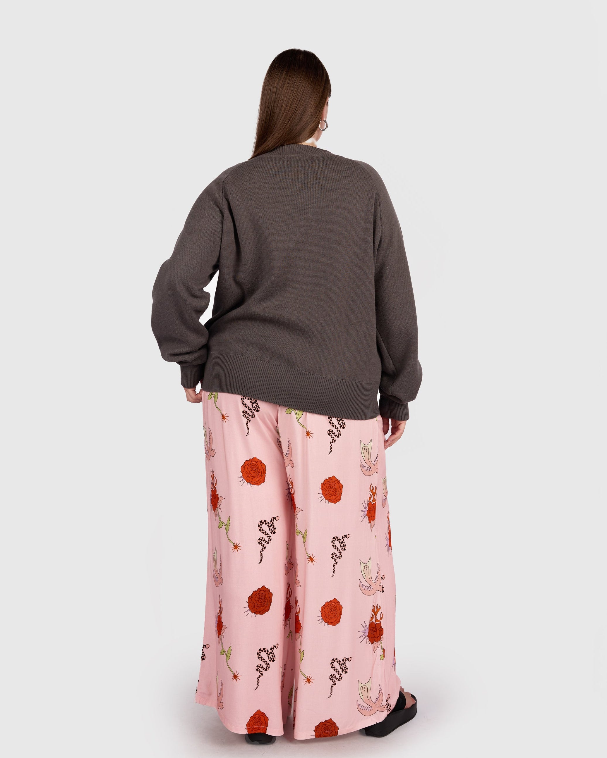 Person wearing a gray sweater and pink floral skirt on a white background