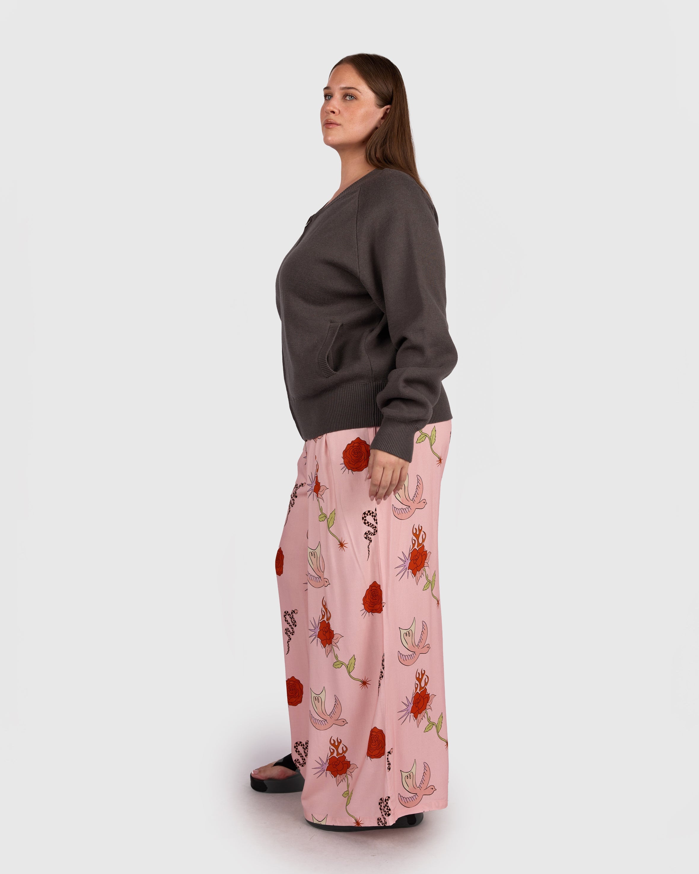 Woman wearing a winter outfit of a knit jacket with long pants. All items are size inclusive and maternity friendly. 