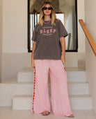 Woman wearing a gray t-shirt with text and pink pants standing on a staircase.