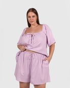 Woman wearing a light purple outfit with a top and shorts on a white background