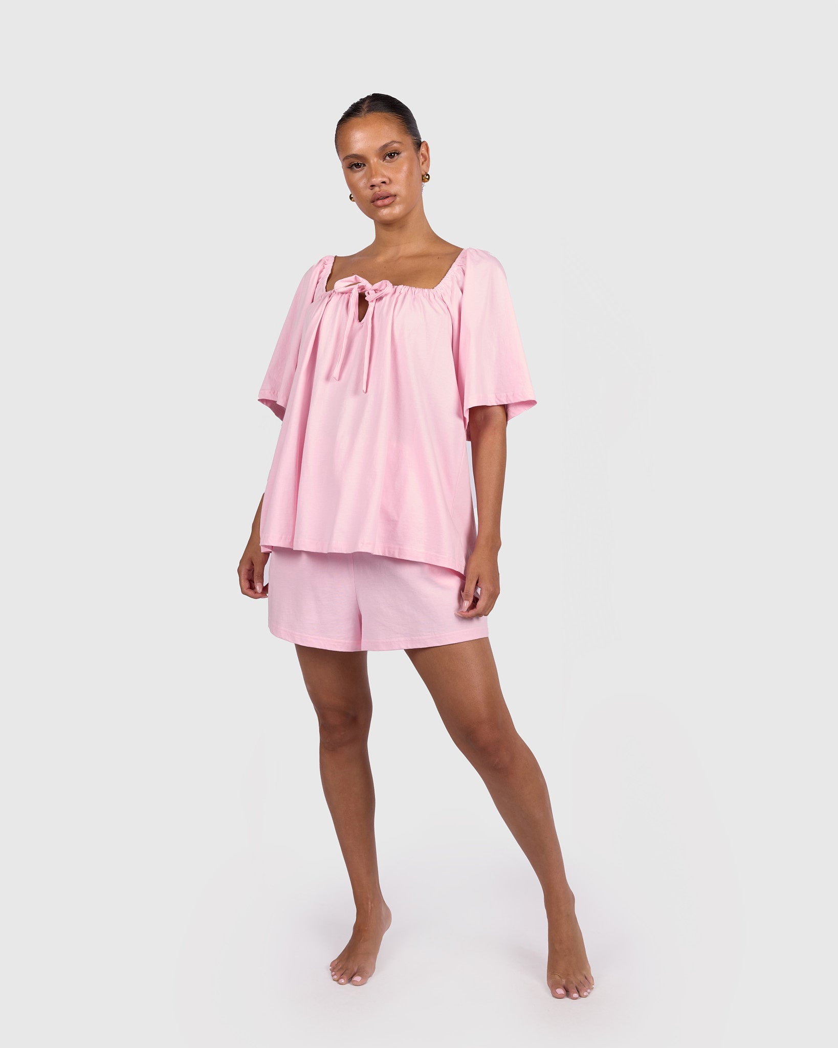Woman wearing a breastfeeding friendly pink pajama set on a white background