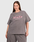 Person wearing a gray oversized t-shirt with 'Certified Sleep Deprived' text on a white background