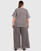Woman wearing a gray outfit with wide-leg pants on a white background