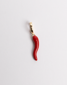 A red and gold-colored charm in the shape of a chili pepper with a gold clasp.