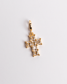 A gold-plated stainless steel diamond cross charm with a white background.