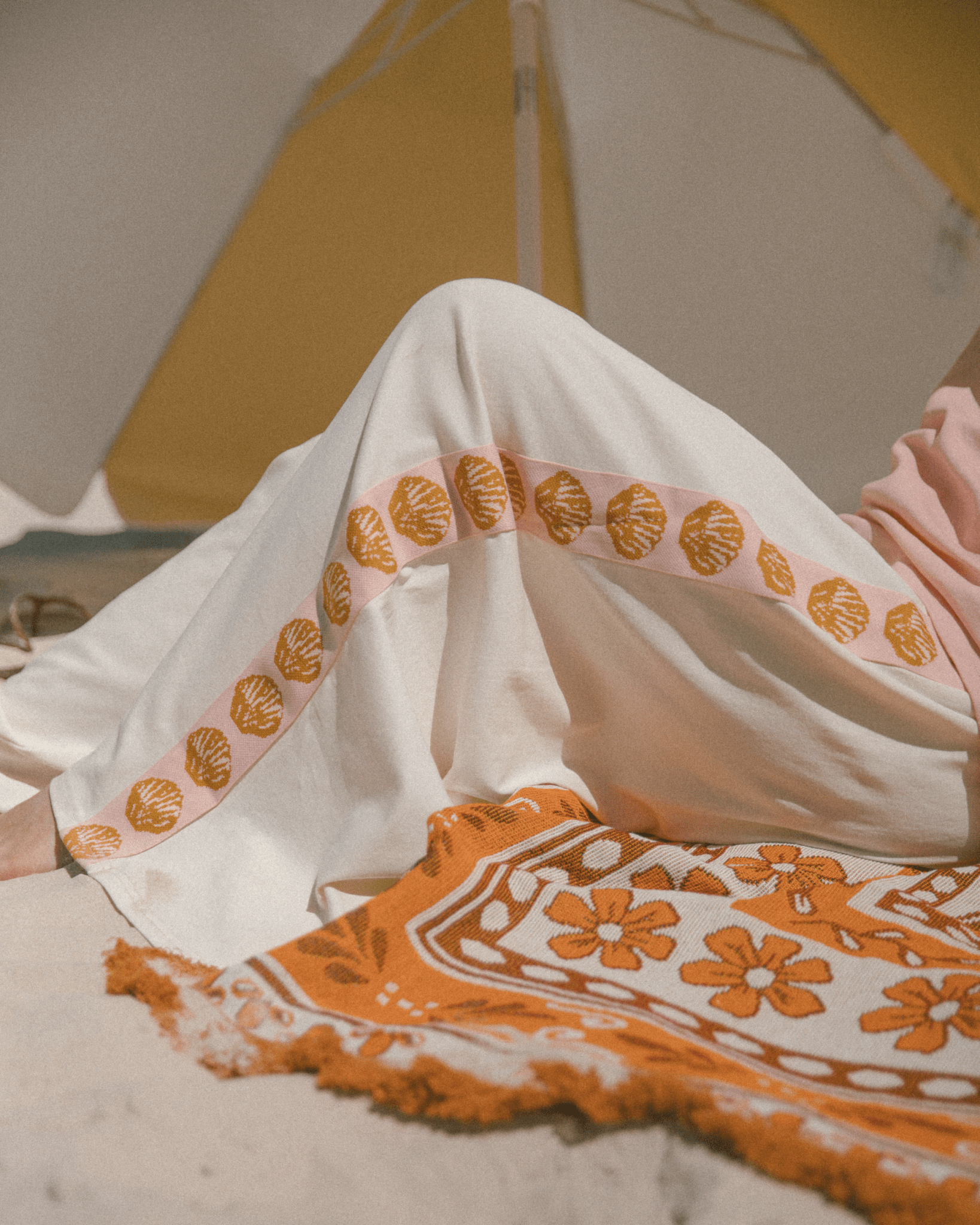 Close up of beige lounge pants with pink & gold shells down the side-seam