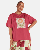 Person wearing a pink t-shirt with a floral design and checkered pants on a white background