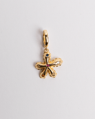 A gold-colored charm in the shape of a flower with a gemstone in the center.