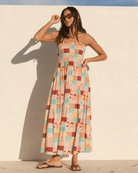 Woman wearing a shirred body strapless dress with a flowy skirt. 