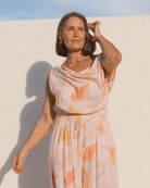 Woman wearing a casual floral spring time outfit, featuring a cowl neck crop top and elastic high-waisted pants. 