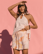 Woman wearing a light pink halter top and high-waisted breathable floral shorts against a pink background