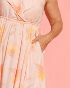 Close up photo of pink floral dress and model with hand in side-pocket.