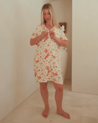 Woman wearing a breathable, button-down nightie, featuring a Australian Christmas pattern. 