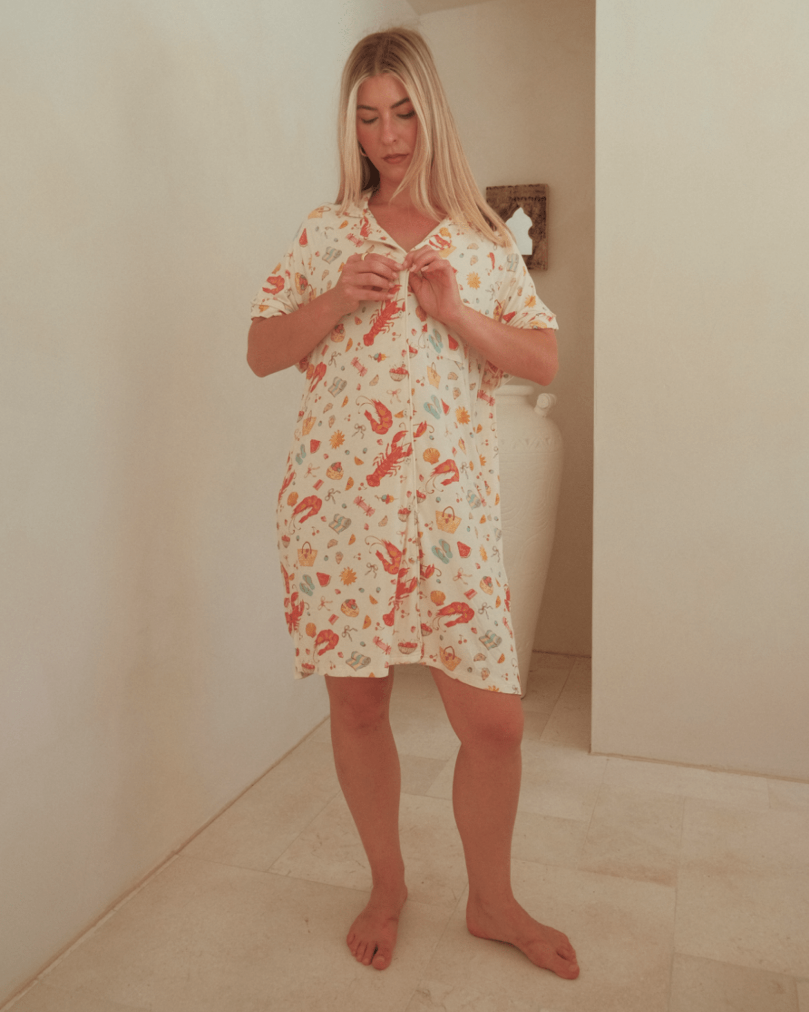 Woman wearing a breathable, button-down nightie, featuring a Australian Christmas pattern. 