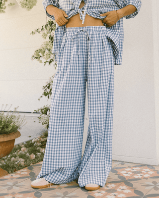 Woman wearing The Lullaby Club Posey Pants in Blue Gingham, featuring a relaxed, oversized fit with an elastic waistband and functional drawstring