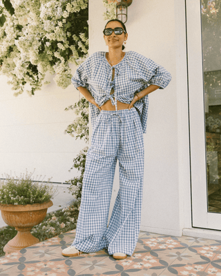 Woman wearing The Lullaby Club Posey Pants in Blue Gingham, featuring a relaxed, oversized fit with an elastic waistband and functional drawstring