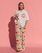 Woman wearing white oversized graphic spring tshirt with high-waisted multicoloured stretchy pants. 