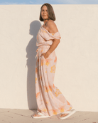 Woman wearing a floral set and standing against a white wall.