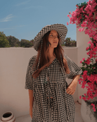Woman in spring black gingham co-ord set with a matching cottage core wide-brimmed hat with adjustable neck ties. 