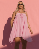 Women wearing pink dress with tie-up detailing on front of the flowy summer dress.